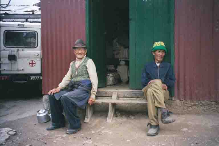 2 Tibetan men waiting for their tea break outside the kitchens at the Tibetan Self-help Centre in Darjeeling